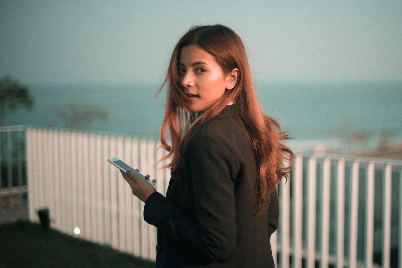 A woman outdoors at dusk, phone in hand
