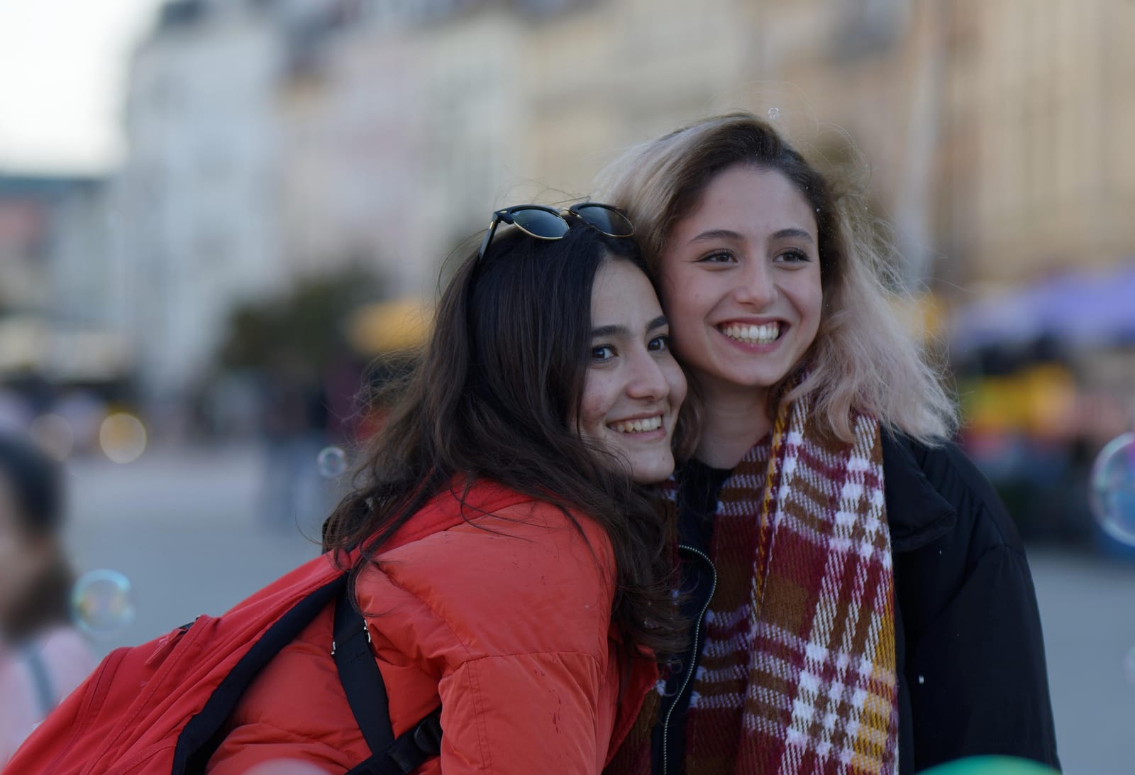 Two friends laughing together on a busy street